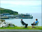 Holidaymakers sitting overlooking Port Erin Bay.